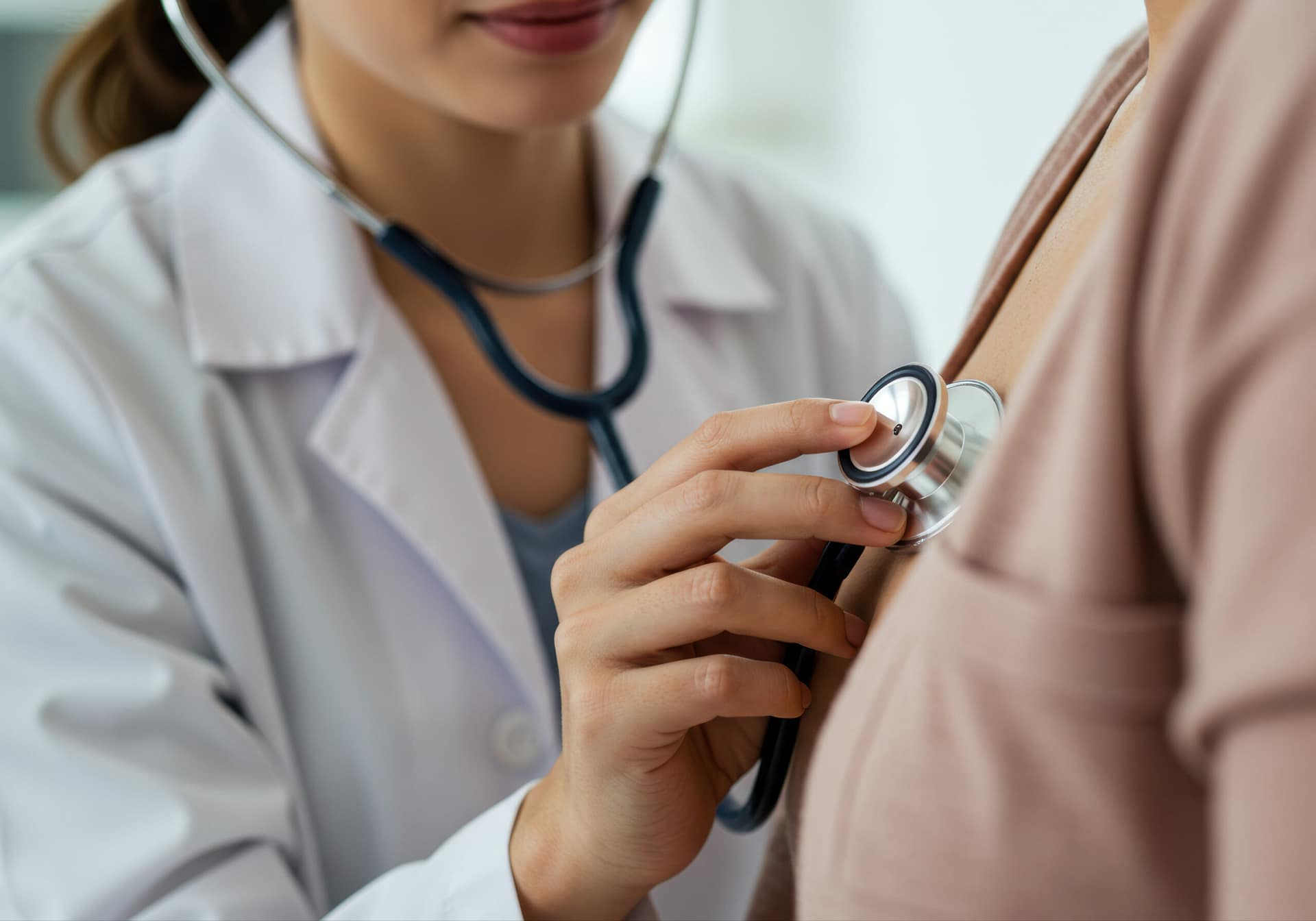 a physician uses a stethoscope to examine a patient's heart during a clinic appointment.