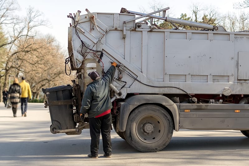 loading rubbish into a garbage truck in a public park on a spring day. waste disposal and cleanliness.